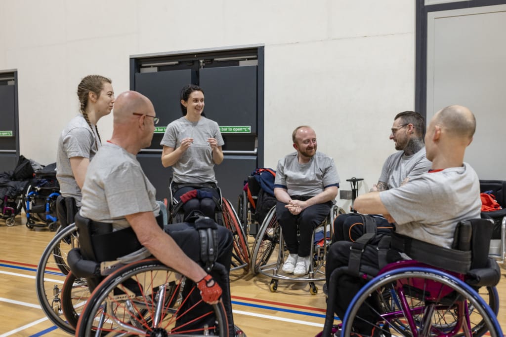 Équipe de personnes en fauteuil roulant jouant au basket-ball dans le nord-est de l'Angleterre. Ils discutent entre eux avant le début de l'entraînement.